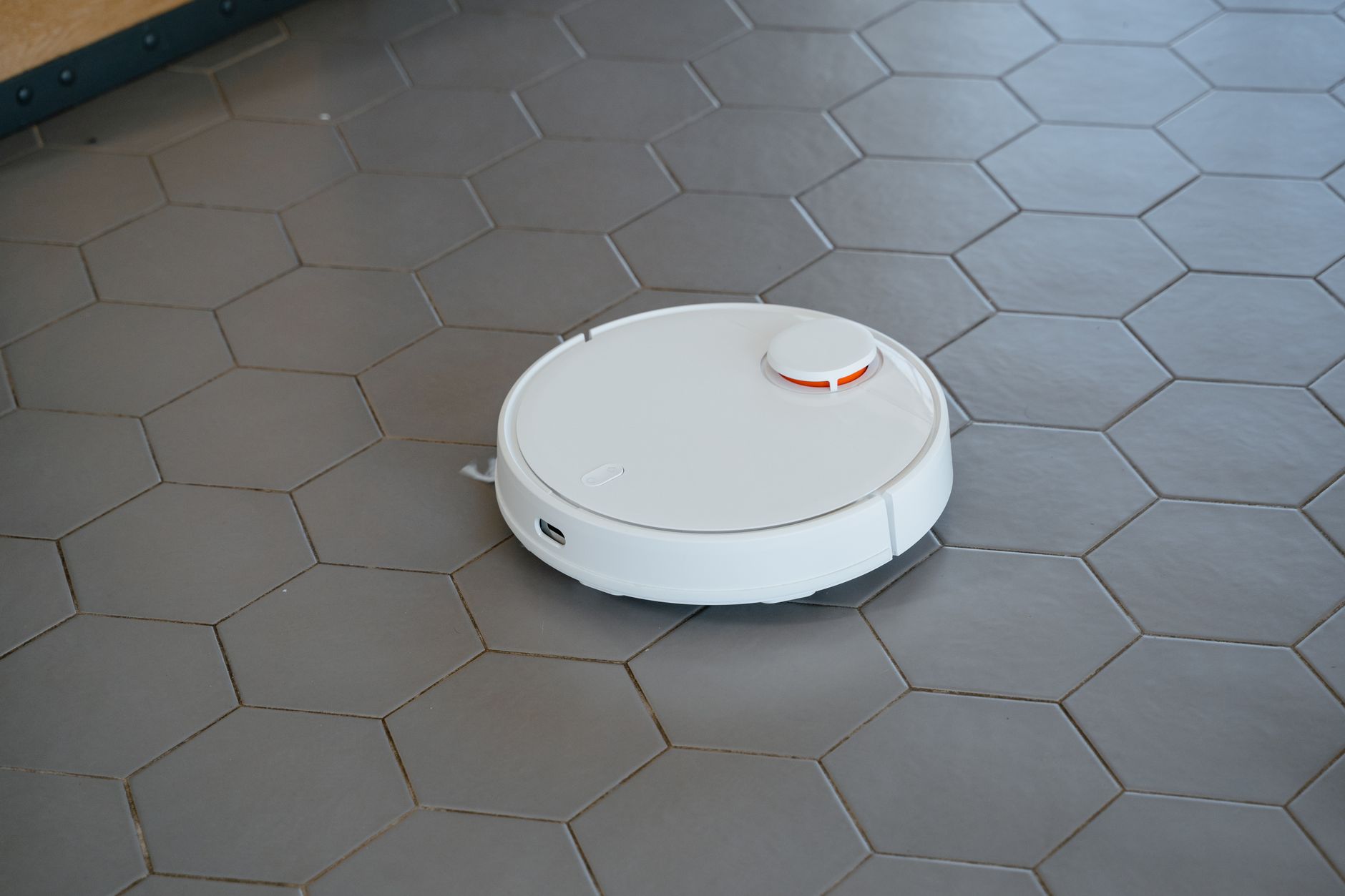 Aspirateur robot circulant sur un carrelage hexagonal