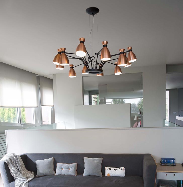 Lustre design cuivré à multiples abat-jour suspendu dans un salon moderne